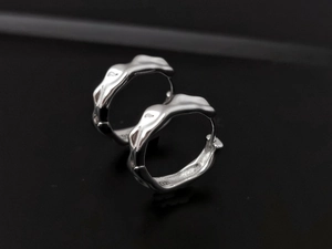 Macro shot of silver S925 earrings with textured wave surface and 925 hallmark stamp