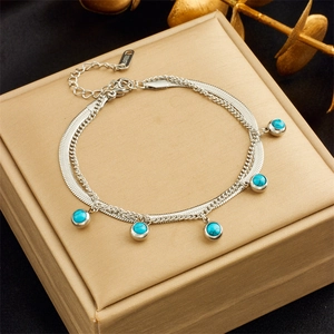 Detail of double-layer stainless steel bracelet with turquoise beads on gold jewelry box