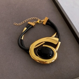 Detail of gold oval black gemstone bracelet with adjustable leather cord and clasp
