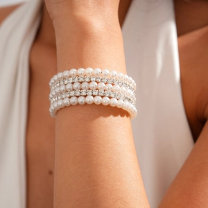 Close-up of multilayer faux pearl bracelet with diamond-encrusted spacers on woman wrist