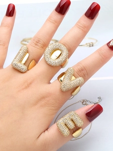Close-up of four gold rings spelling LOVE with clear zircons on a hand with red nails