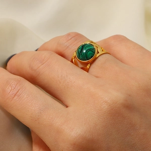 Detailed close-up of 18K gold ring featuring a round green malachite stone on finger