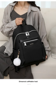 Close-up of black nylon backpack with silver zippers and a white pom-pom pendant