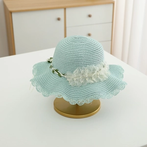 Close-up of mint green straw sun hat with lace edge and white chiffon flower detail