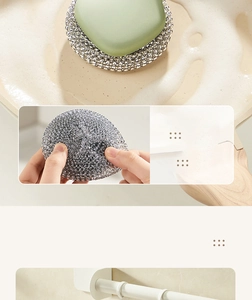 Detail of silver metal scouring pad with green handle cleaning a soapy cooking pot