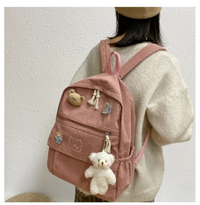 Detalle de mochila de pana rosa con colgante de oso adorable llevada por modelo