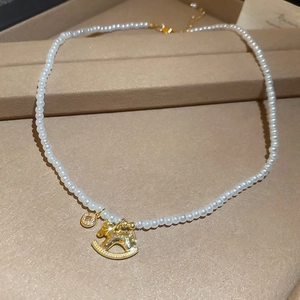 Detailed macro shot of vintage pearl necklace with golden horse and letter B pendants