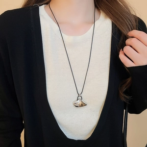 Close-up of irregular silver polished pendant on a black cord for a modern look