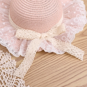 Close-up of pink straw sun hat showing intricate woven texture and white lace bow detail