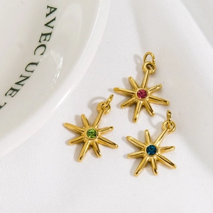Gold eight-pointed star pendants with colorful inset gems on white textured fabric