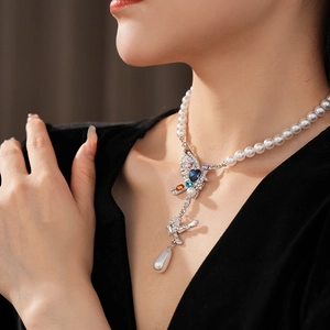 Détail d'un collier vintage avec pendentif oiseau coloré et perle en forme de goutte