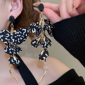 Detail of vintage leopard print fabric flower earrings with long gold tassel on a model