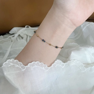 Primo piano del braccialetto con perline blu stellate al polso su sfondo di pizzo elegante