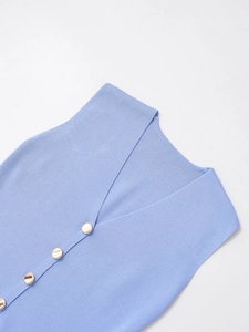Détail du gilet en maille bleu clair avec col en V et boutons ronds dorés décoratifs