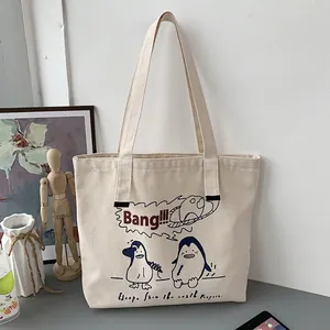 Close-up of beige canvas tote bag with penguin print and wide shoulder straps