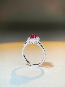 Macro shot of oval red zircon center stone with halo pave settings on a silver band