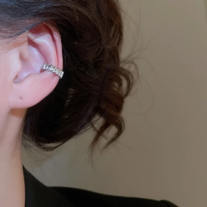 Detailed view of silver cuff earring with rectangular zircons on female ear