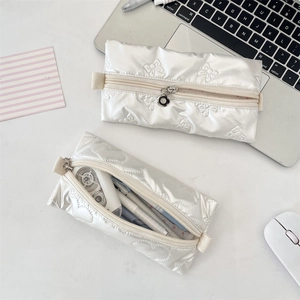 Detail of white quilted PU pencil cases with bow and heart accents and flower zipper