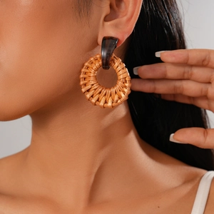Detailed view of handmade woven rattan round earrings on model for bohemian summer style