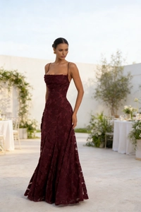 Close-up detail of burgundy red lace fabric and floral pattern on a slim evening gown