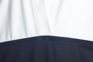 Détail de couture contrastée bleu marine et blanc sur le tissu en maille extensible