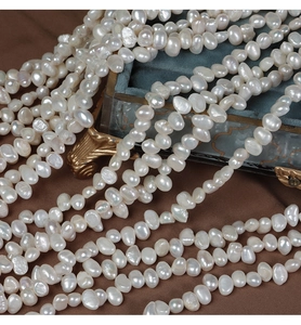 Macro shot of 6-7mm white baroque freshwater pearls stacked in a vintage blue jewelry box