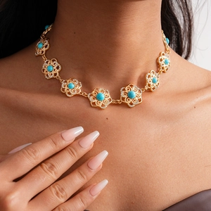 Detail of luxury gold hollow flower necklace with blue stones and crystals on neck