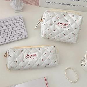 Vue détaillée de la trousse de maquillage matelassée blanche avec motif de cerise.
