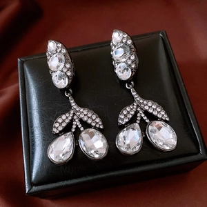 Détail des boucles d'oreilles pendantes avec feuilles et strass sur du cuir