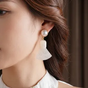 Elegant gold earrings with round white pearl and marble texture fan pendant on model
