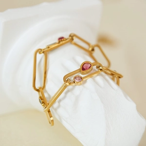 Détail du bracelet chaîne dorée avec zircons colorés sur socle blanc