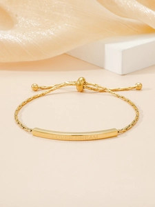 Detail of adjustable gold stainless steel bracelet with engraved bar and woven chain