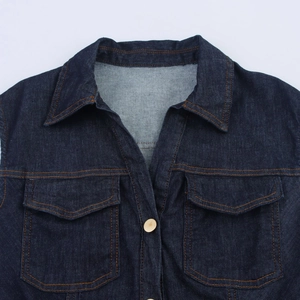 Détail du col à revers et des poches poitrine de la robe en jean avec coutures orange