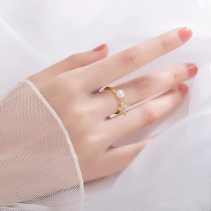 Detail eines goldenen Schmetterlingsrings mit weißer Süßwasserperle am Finger