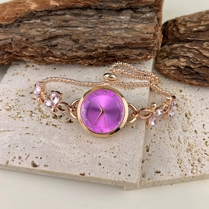 Rose gold bracelet watch featuring a purple dial and pink crystal accents on stone