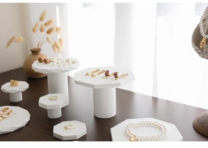 Detailansicht von Goldschmuck und weißen Perlen auf minimalistischen achteckigen Gipsständern