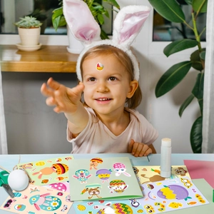 Niña con orejas de conejo usando pegatinas de huevos de Pascua para manualidades infantiles