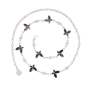 Chaîne de taille argentée avec papillons pailletés noirs et cristaux sur fond blanc