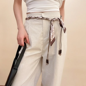 Détail d'une ceinture foulard en soie vintage avec perles en bois sur pantalon beige