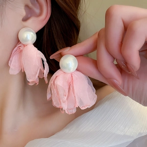 Close-up of pink mesh flower and pearl earrings on ear with delicate chiffon texture