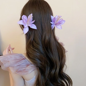 Detail of light purple floral hair clips with realistic petals on long wavy brown hair