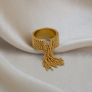Detail of a gold-plated stainless steel ring featuring delicate metallic bead tassels