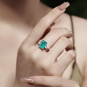 Close-up of 925 silver ring featuring emerald-cut Paraiba tourmaline and pear-shaped side diamonds