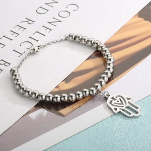 Detailed view of silver beaded Hamsa Hand bracelet with heart cutout on art background