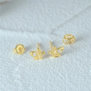 Macro detail of gold butterfly stud earrings with sparkling cubic zirconia on white texture