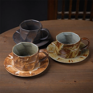 Close-up of octagonal ceramic coffee cups with textured glaze on a dark wooden table
