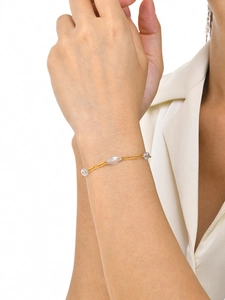 Detailed view of a gold stainless steel bracelet with zircon and pearls on a model's wrist