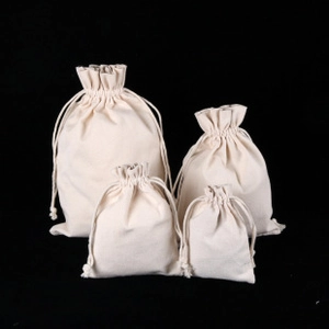 Detail of four sizes of off-white canvas drawstring bags against a black background