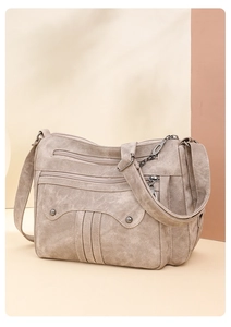 Detail view of khaki crossbody bag with multi-zipper pockets and rivet decorations