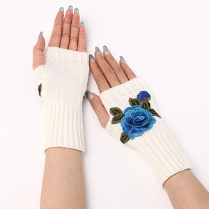 Detail of cream knit fingerless gloves featuring blue rose embroidery on hands